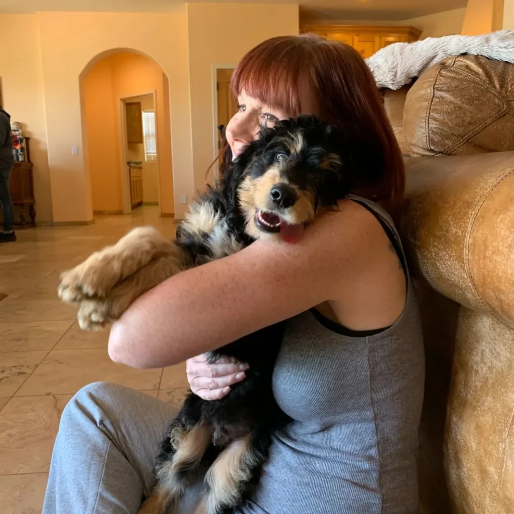 Woman Hugging a color black and brown puppy